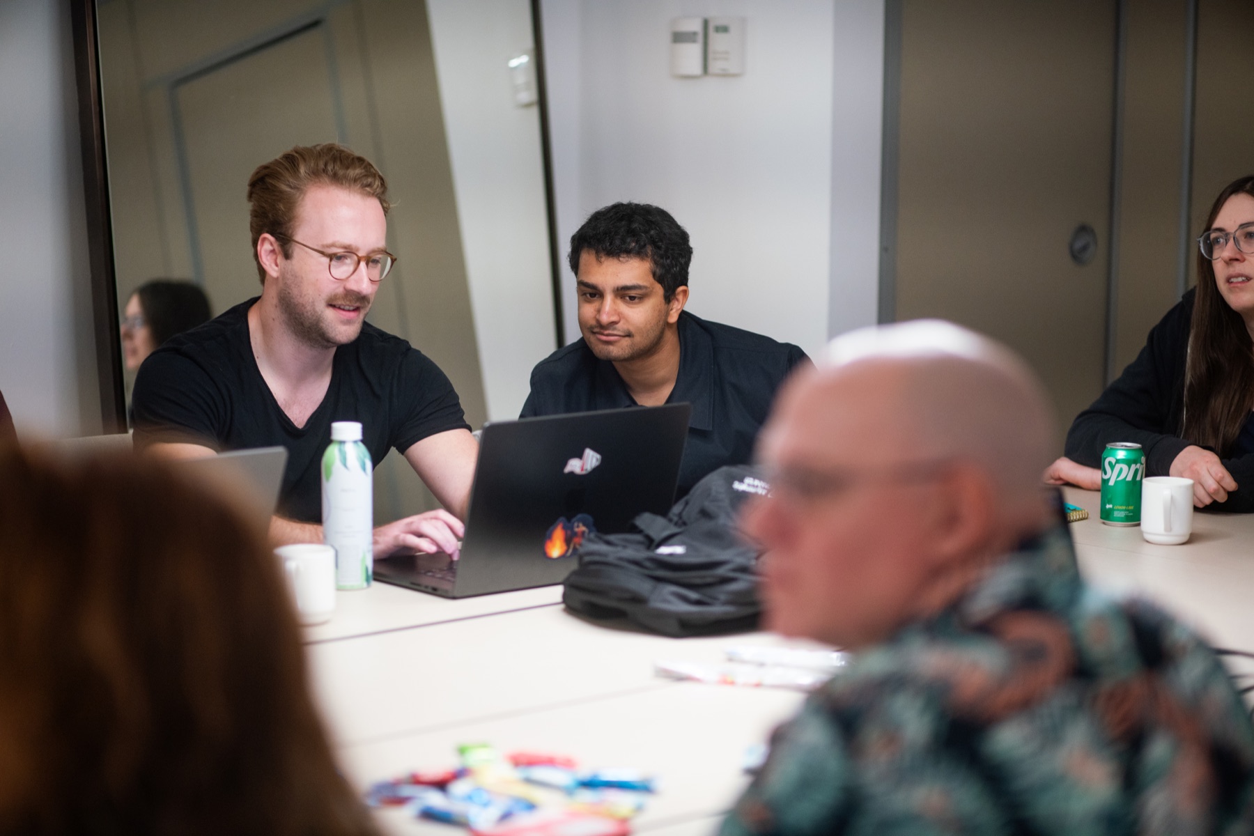 Teammates working together around a laptop during the Miami offsite.