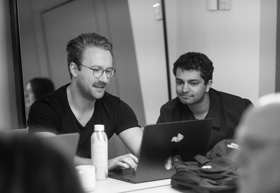 Two teammates working together on a laptop.